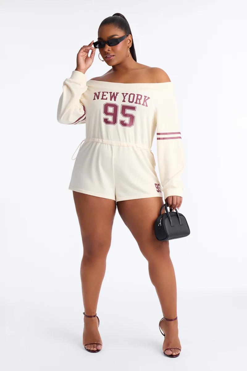 Confident woman modeling a blue & white striped plus size romper with drawstring waist, white sneakers, and black shoulder bag.