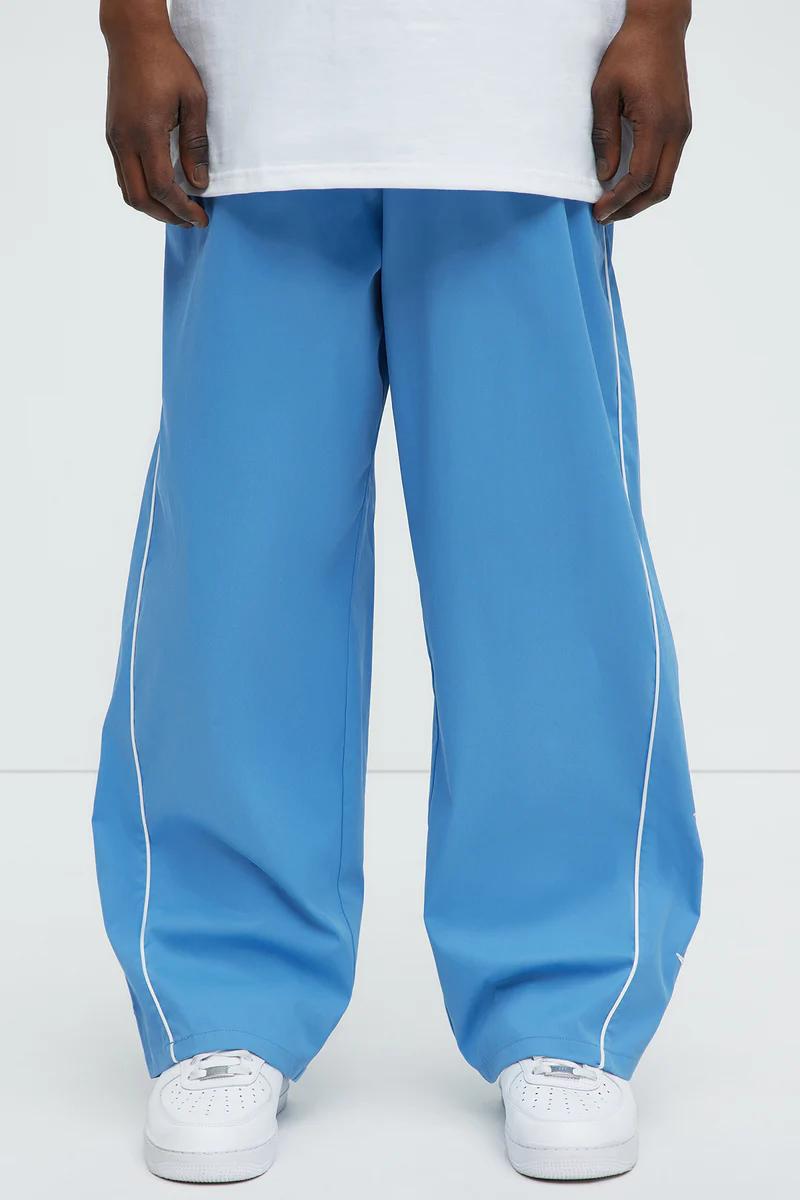 Modelo en pantalones anchos azules con raya blanca y zapatillas. Descubre nuestra nueva colección de ropa casual para hombre.