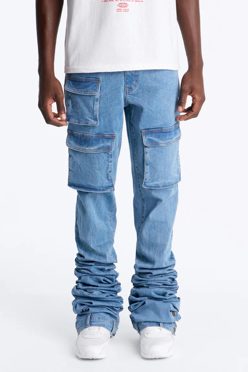 Modelo en jeans cargo apilados lavado claro, bolsillos grandes y tobillos fruncidos, sobre zapatillas blancas. Destaca mezclilla urbana.