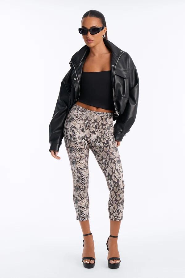 Woman wearing snakeskin print cropped leggings, a black leather jacket, and heels, showcasing edgy new season streetwear fashion.
