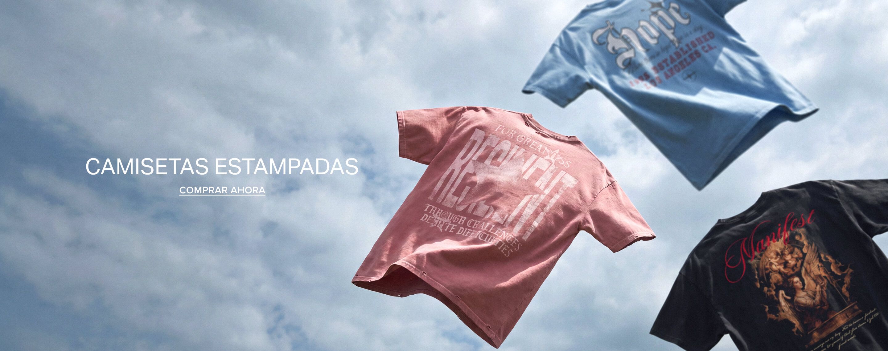 Camisetas con gráficos en azul, rosa y negro flotando en un cielo nublado con texto que promueve comprar ahora la nueva colección.