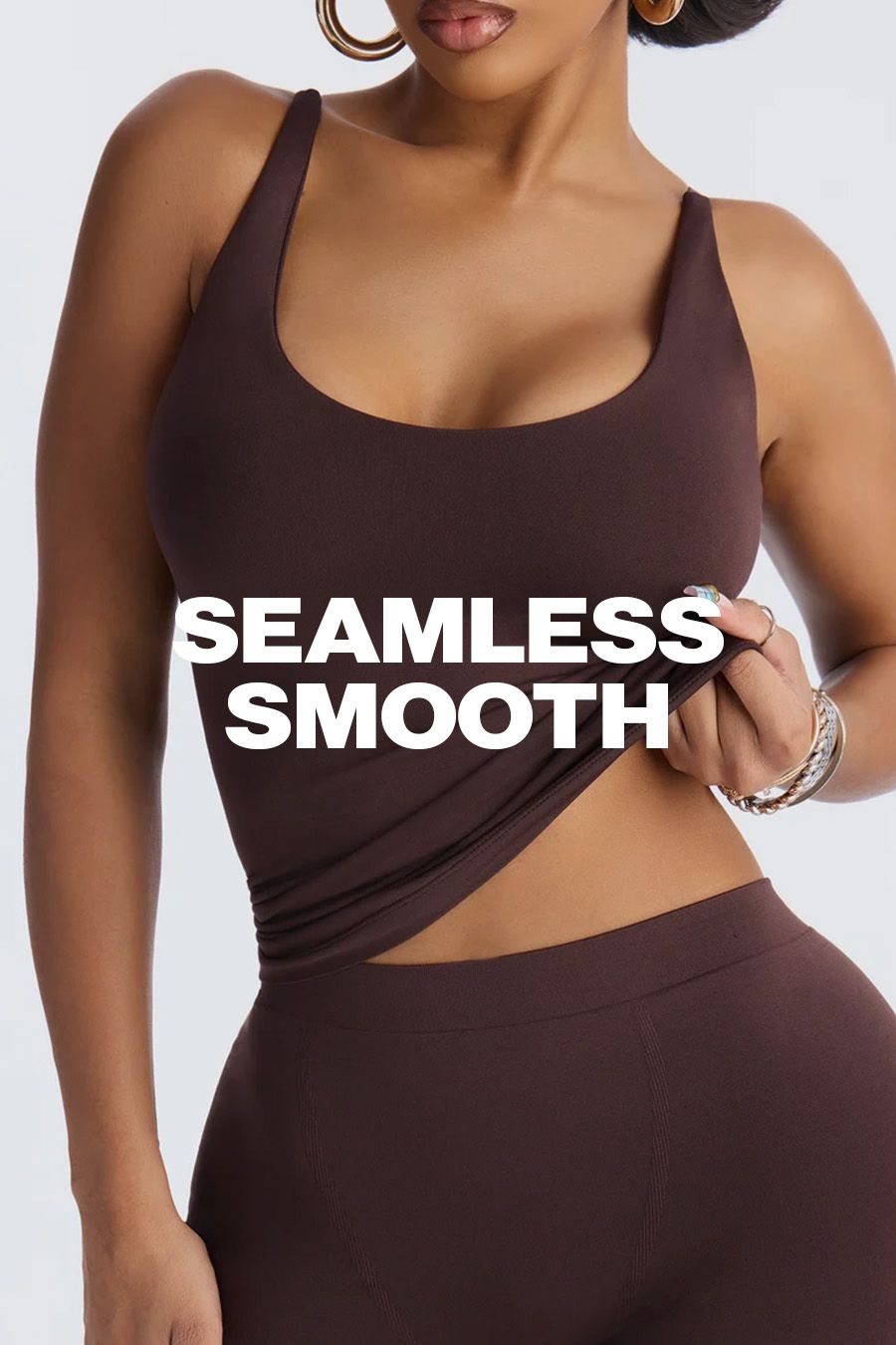 Woman in a brown seamless activewear set lifting her tank top, promoting the smooth, stretchy fabric. Text overlay reads: SEAMLESS SMOOTH.