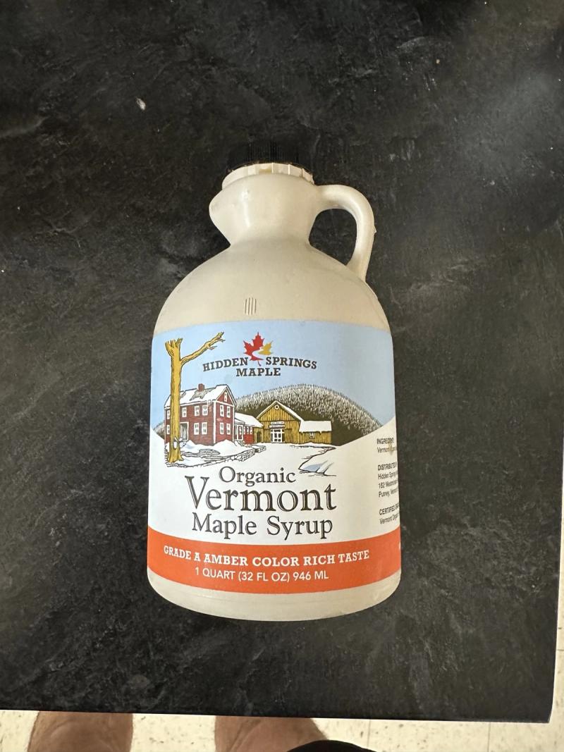 A one-quart jug of Hidden Springs organic Vermont maple syrup on a dark counter