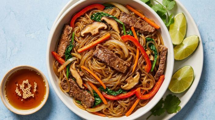 A colorful bowl of Korean Japchae noodles with beef and vegetables.