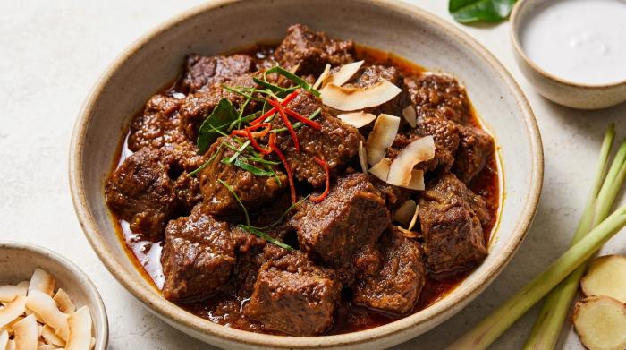 Dark brown beef rendang coated in a thick, dry curry paste served next to white rice.