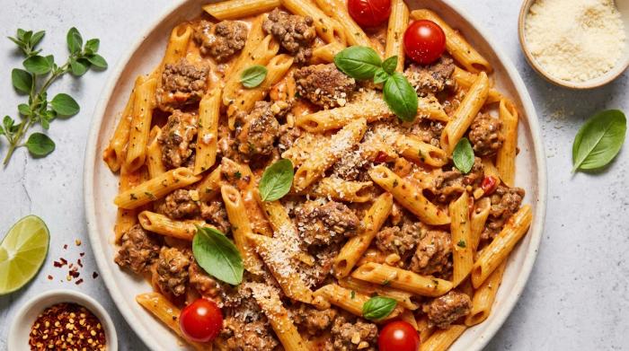A warm bowl of creamy tomato beef pasta garnished with parsley.