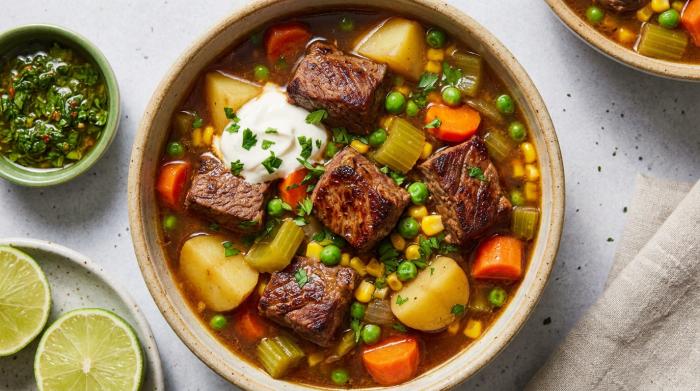 A rustic bowl of hearty vegetable beef soup with chunks of tender meat and potatoes.