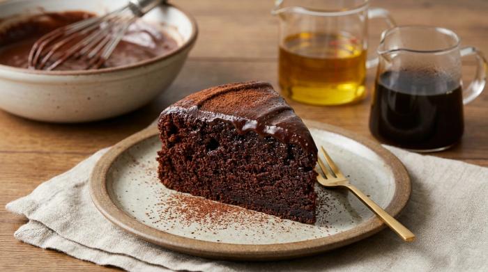 A decadent slice of frosted chocolate cake on a dessert plate.