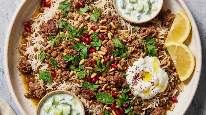 Middle Eastern lamb and lentil rice pilaf garnished with crispy shallots and served with fresh sliced tomatoes.