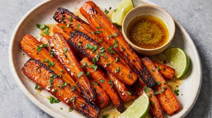 Shiny brown sugar glazed carrots with deep brown roasted edges on a white plate.