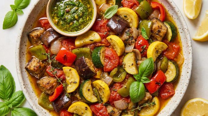 A bowl of vibrant ratatouille garnished with fresh basil leaves.