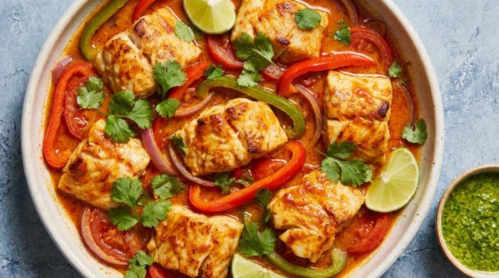 A close-up of a rich, creamy coconut fish stew garnished with fresh cilantro.