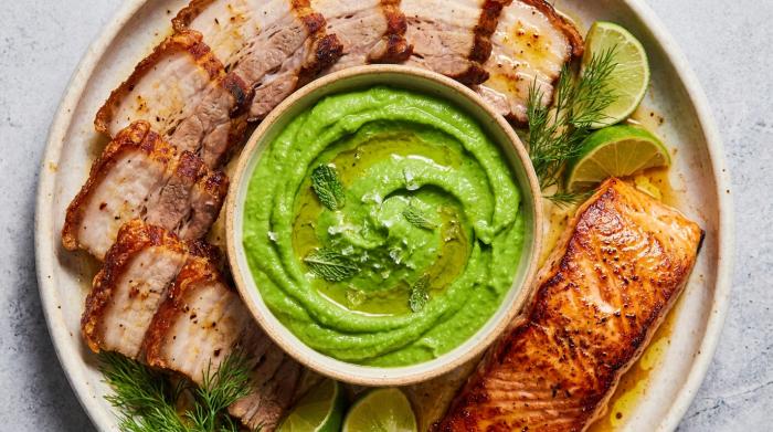 Vibrant green pea puree smeared artistically on a white plate.