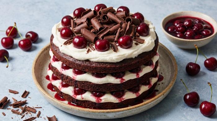 A whole Black Forest Cake topped with fresh cream rosettes, maraschino cherries, and chocolate curls.