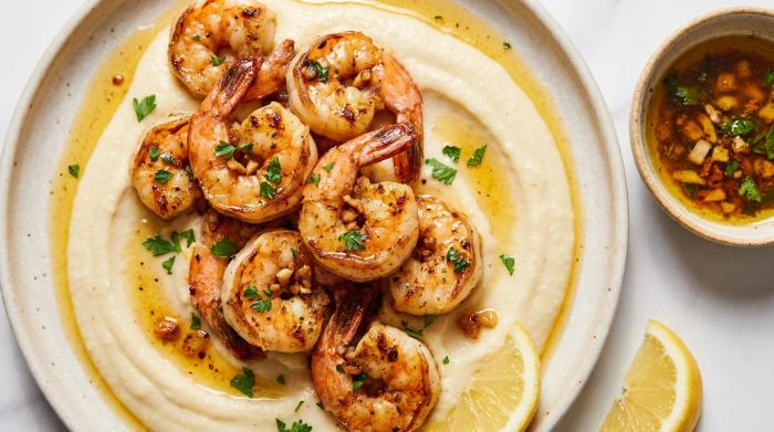 Close-up of garlic prawns drizzled with browned butter on a bed of cauliflower puree.