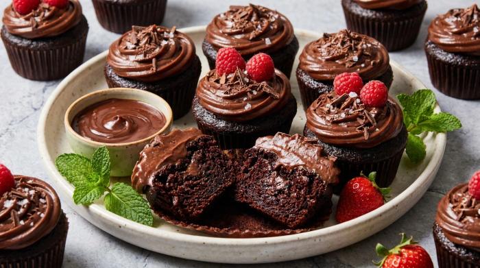 A batch of moist chocolate cupcakes topped with swirls of chocolate frosting.