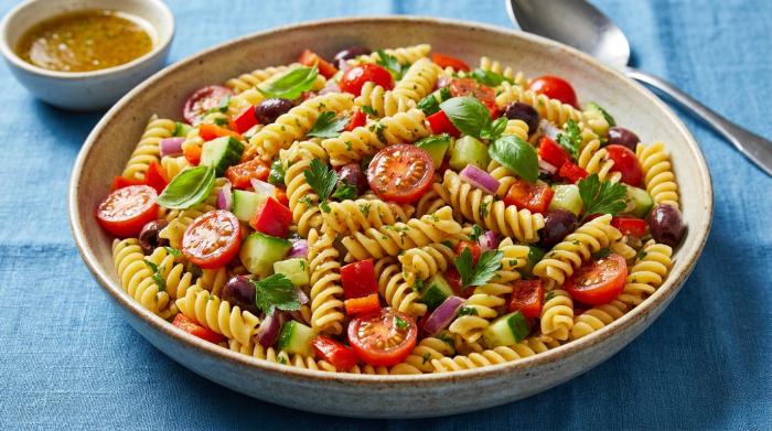 A bright, colorful bowl of mixed pasta salad.