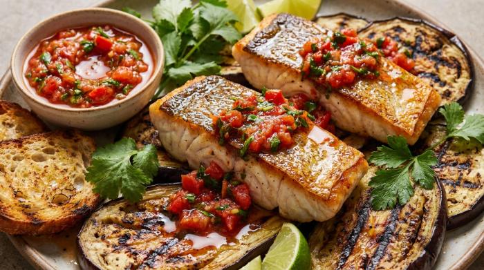 A plate of pan-fried fish with fresh tomato salsa over charred eggplant.