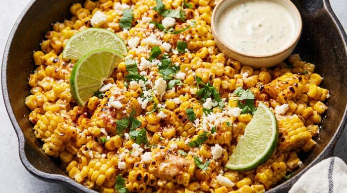 A serving bowl filled with creamy Mexican corn salad topped with cotija cheese and fresh cilantro.