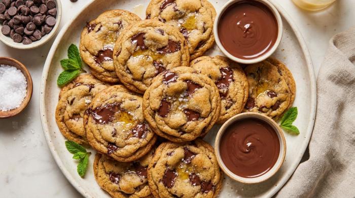 Stack of large, soft chocolate chip cookies with melted chocolate chips on a surface.
