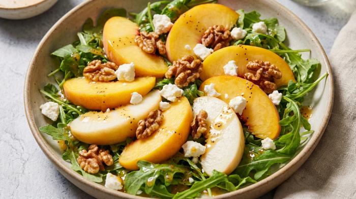 A large bowl of vibrant peach salad topped with poppyseed dressing