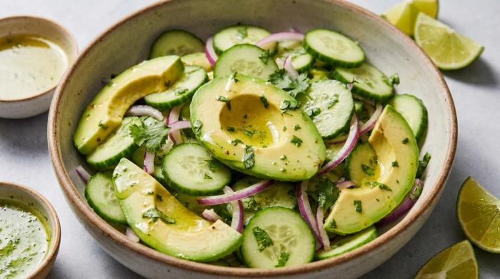 Close-up of freshly tossed avocado and cucumber salad with herbs.