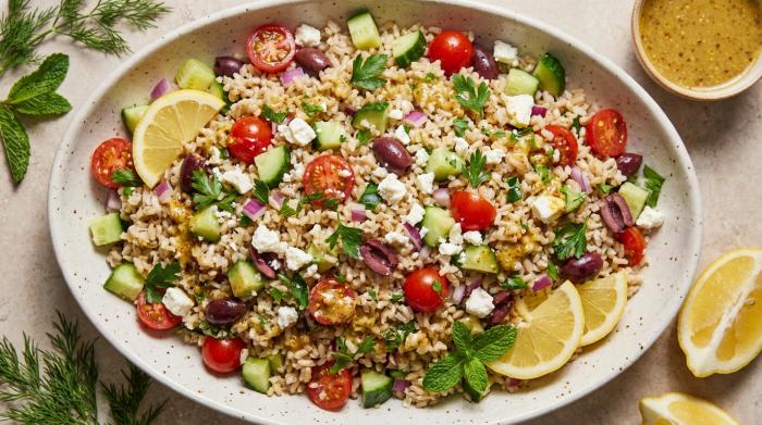 A large serving bowl filled with Mediterranean brown rice salad topped with halloumi.