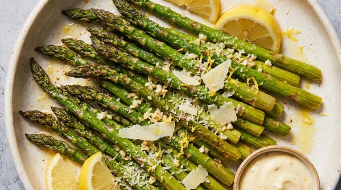 A serving platter filled with bright green roasted asparagus, seasoned and topped with grated parmesan cheese