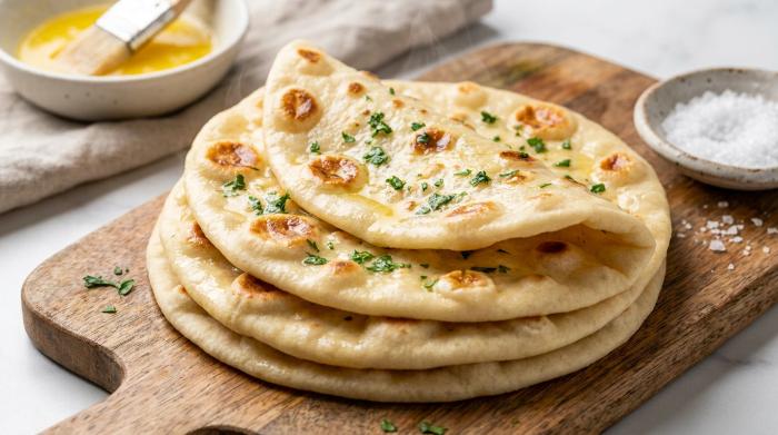 A stack of freshly cooked, pliable flatbreads with golden brown spots.