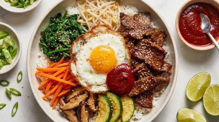 Assembled bibimbap bowl with colorful vegetables and a sunny side up egg on top.