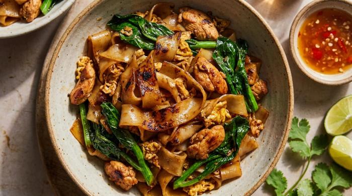 A plate of Pad See Ew with chicken and Chinese broccoli