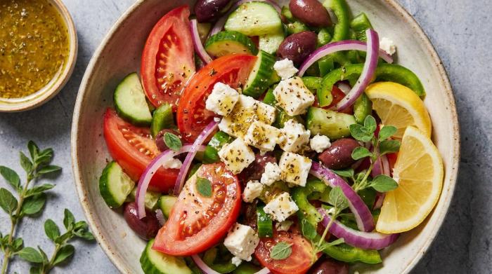 A fresh Greek salad with chunky tomatoes, cucumbers, feta cubes, red onions, and black Kalamata olives.