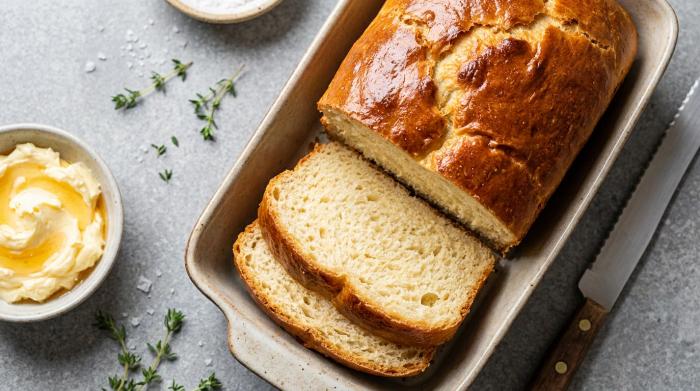 A sliced loaf of sandwich bread without yeast next to butter.