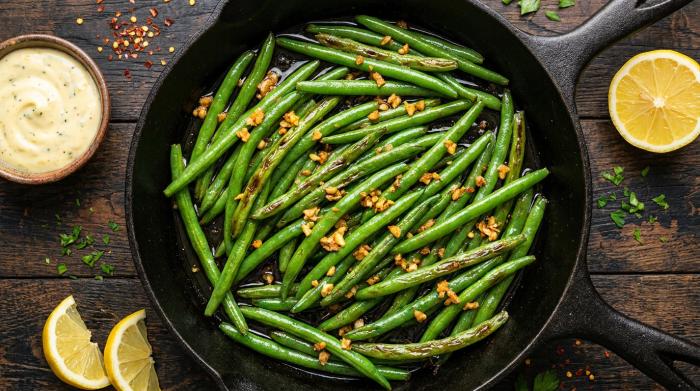 A serving dish filled with bright green sauteed beans and golden garlic bits.