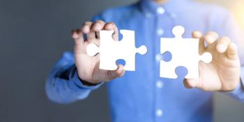 Businessman hands connecting puzzle pieces representing the merging of two companies or joint venture, partnership, Mergers and acquisition concept. | Image credit: © Worawut-stock.adobe.com