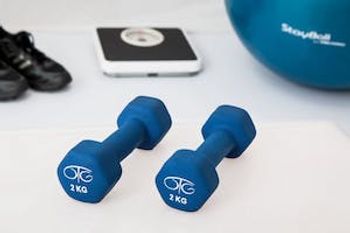 exercise equipment including weights, a scale, sneakers, and an exercise ball