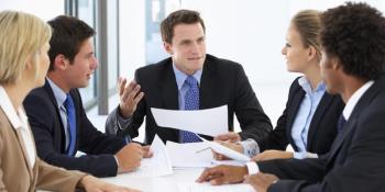 people in suits sitting around a table talking
