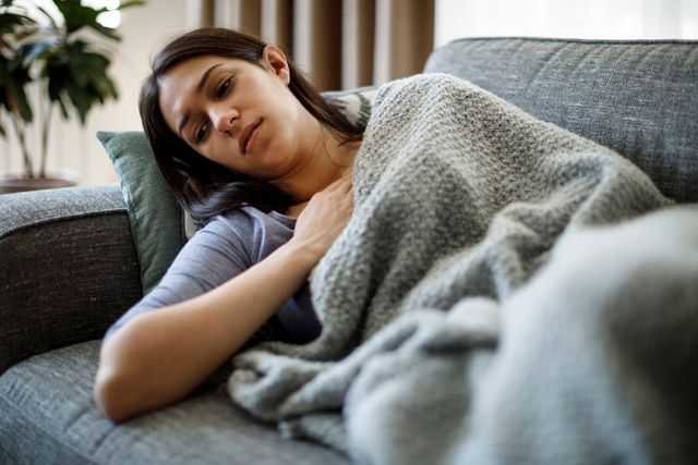 a fatigued woman on the couch with a blanket