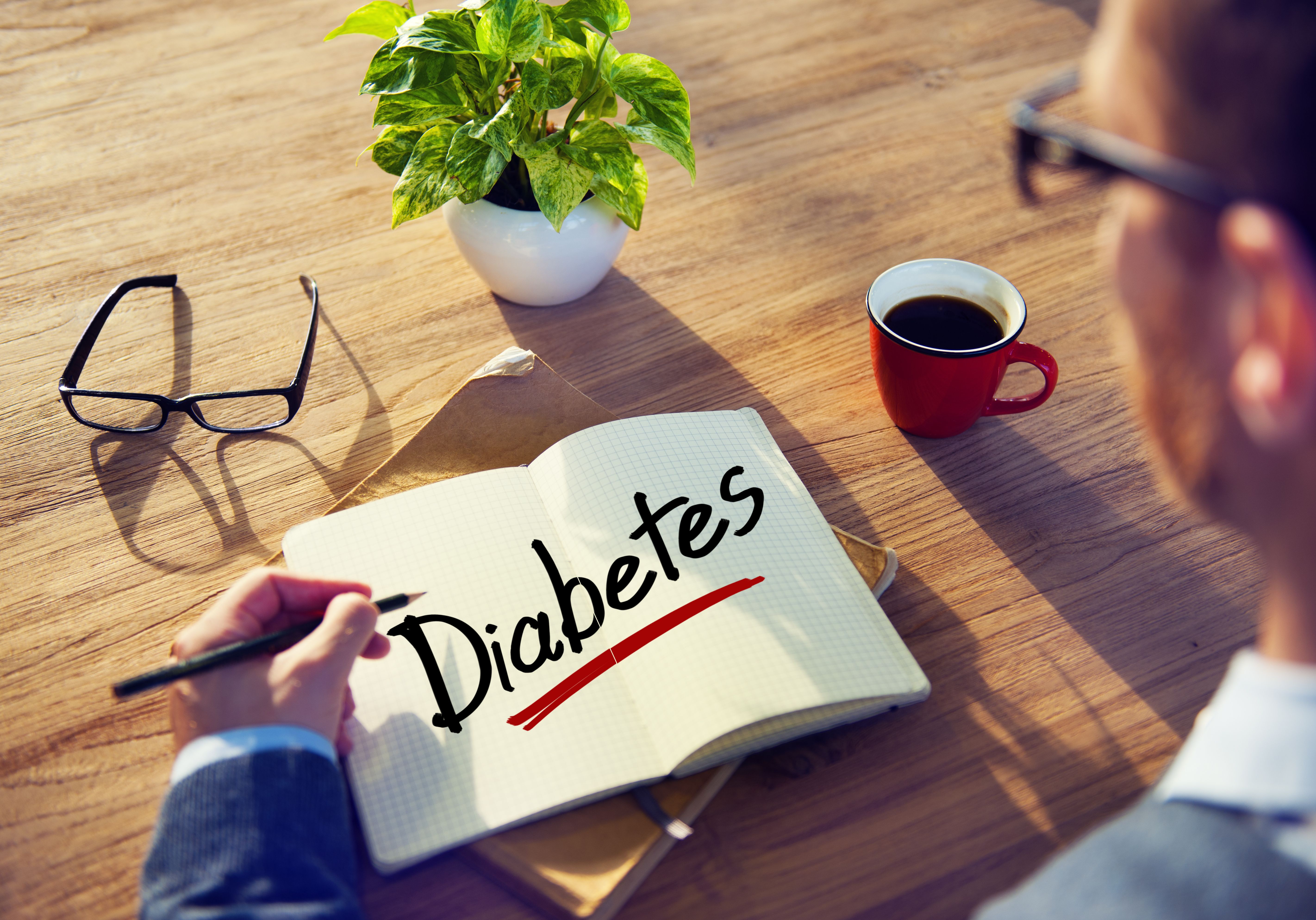 man sitting in front of notebook with "diabetes" written on it