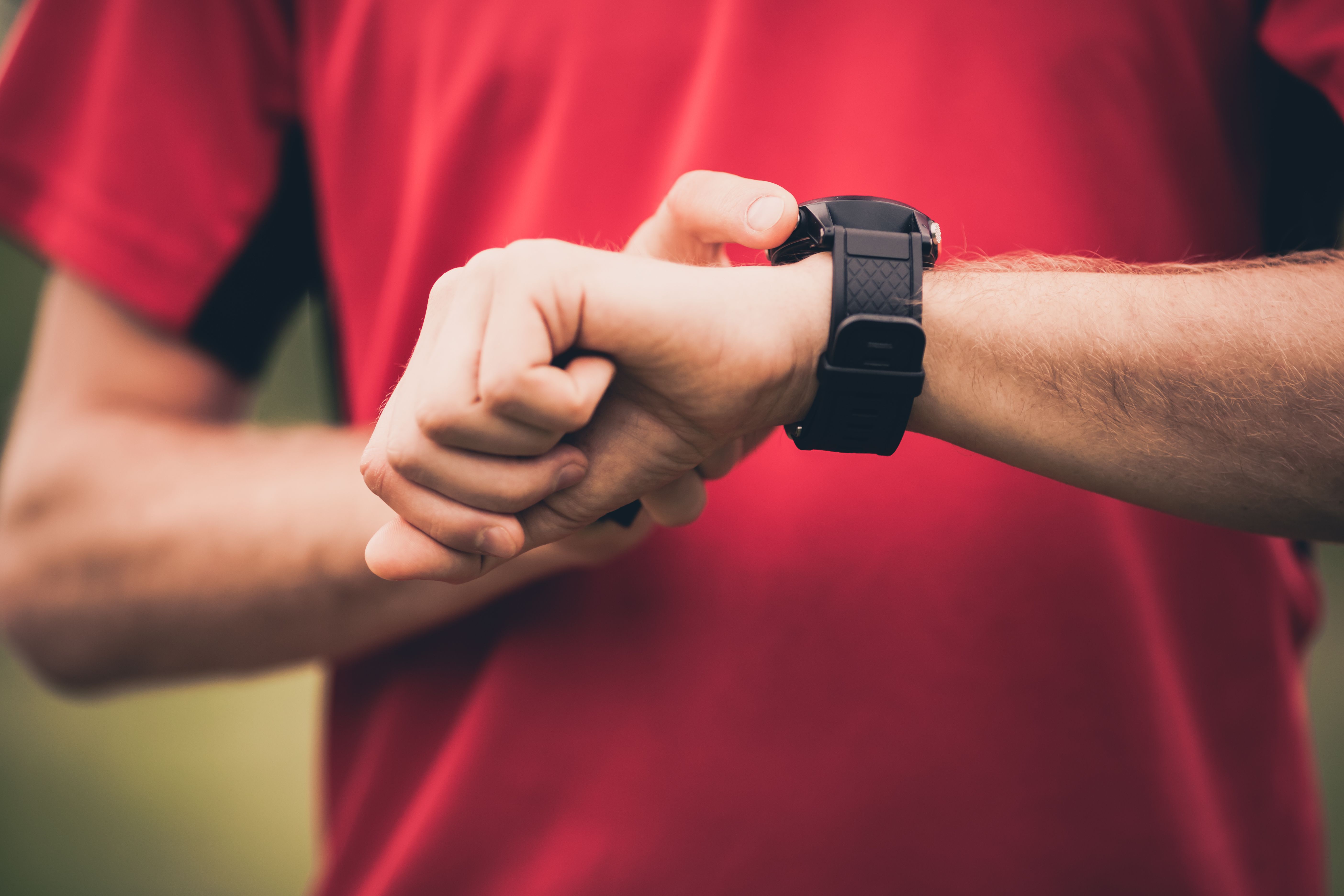 man in red t shirt looking at watch