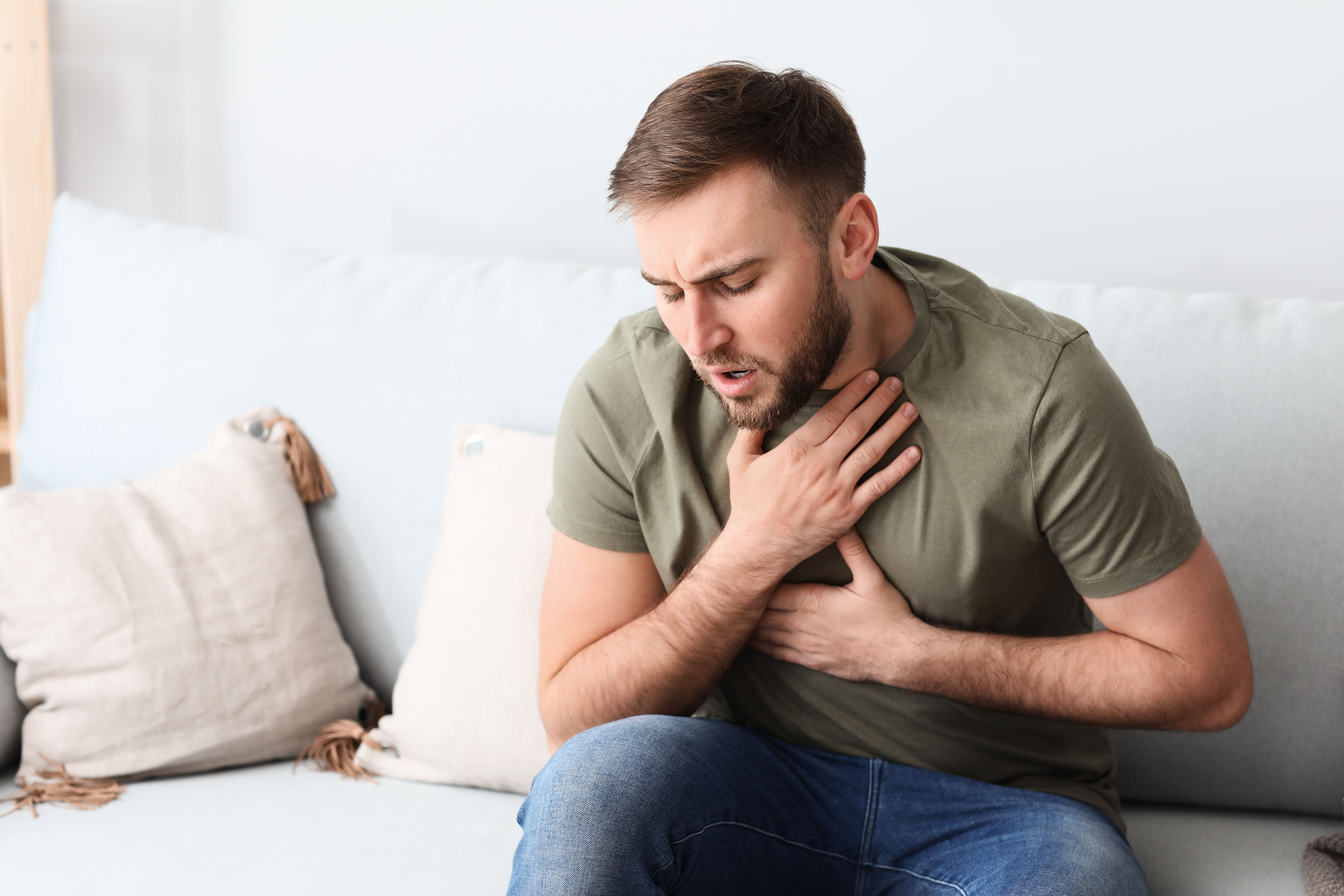 Man having asthma attack on couch | Image credit: Pixel-Shot – stock.adobe.com