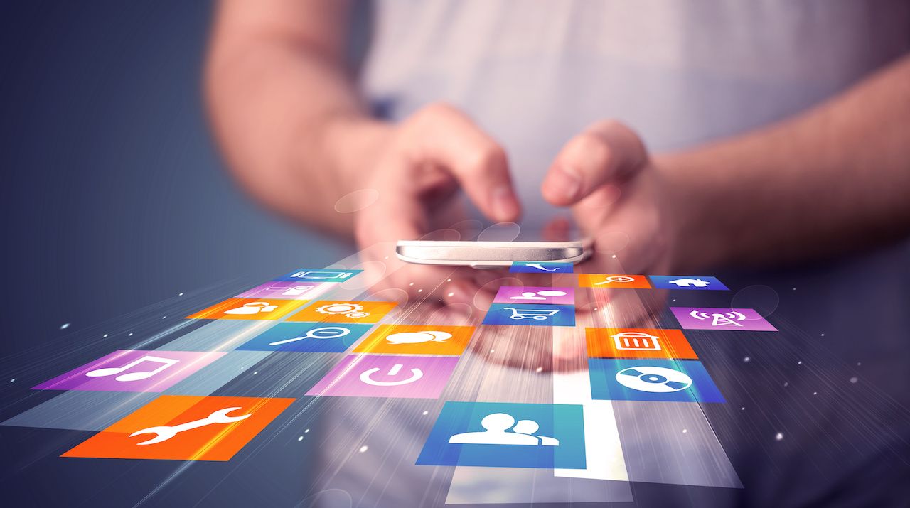 Man holding smart phone with colorful application icons: © ra2 studio - stock.adobe.com