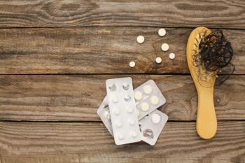 Hair loss in brush and medicine on table | Image Credit: Viktoriia M - stock.adobe.com