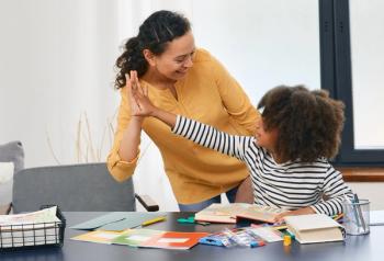 Child and therapist high-fiving | Image credit: Peakstock – stock.adobe.com