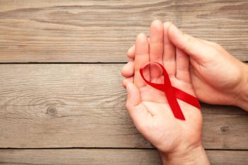 A female hands holding an aids red ribbon on grey | Image credit: Mouse family - stock.adobe.com