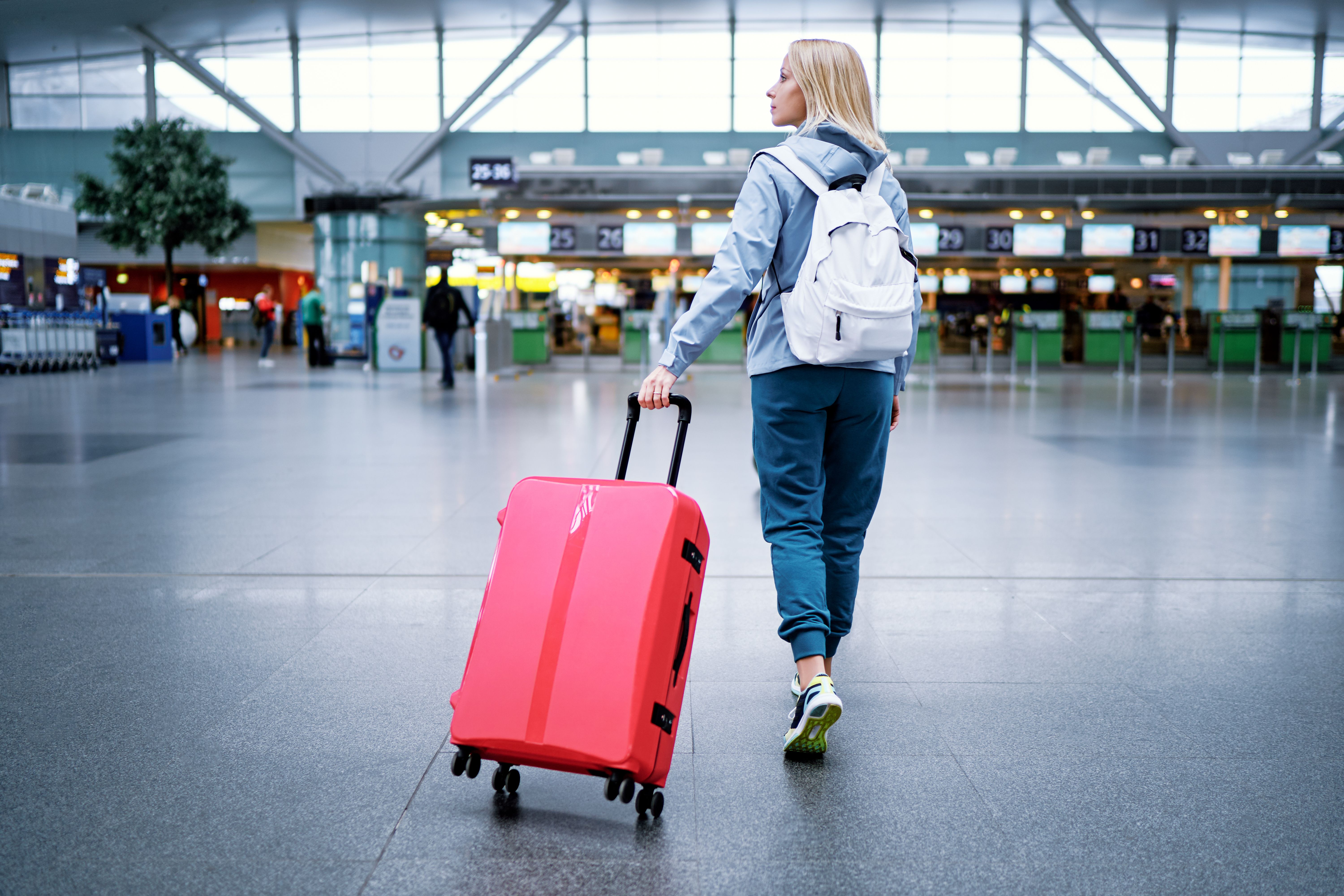 Traveling concept. Young woman in casual wear standing in international airport terminal. - luengo_ua - stock.aobe.com