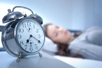 woman sleeping with an alarm clock in focus