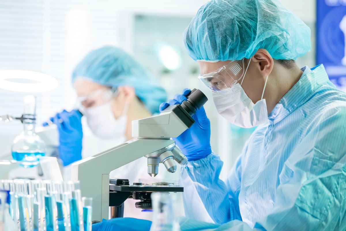 Scientists using microscope in lab