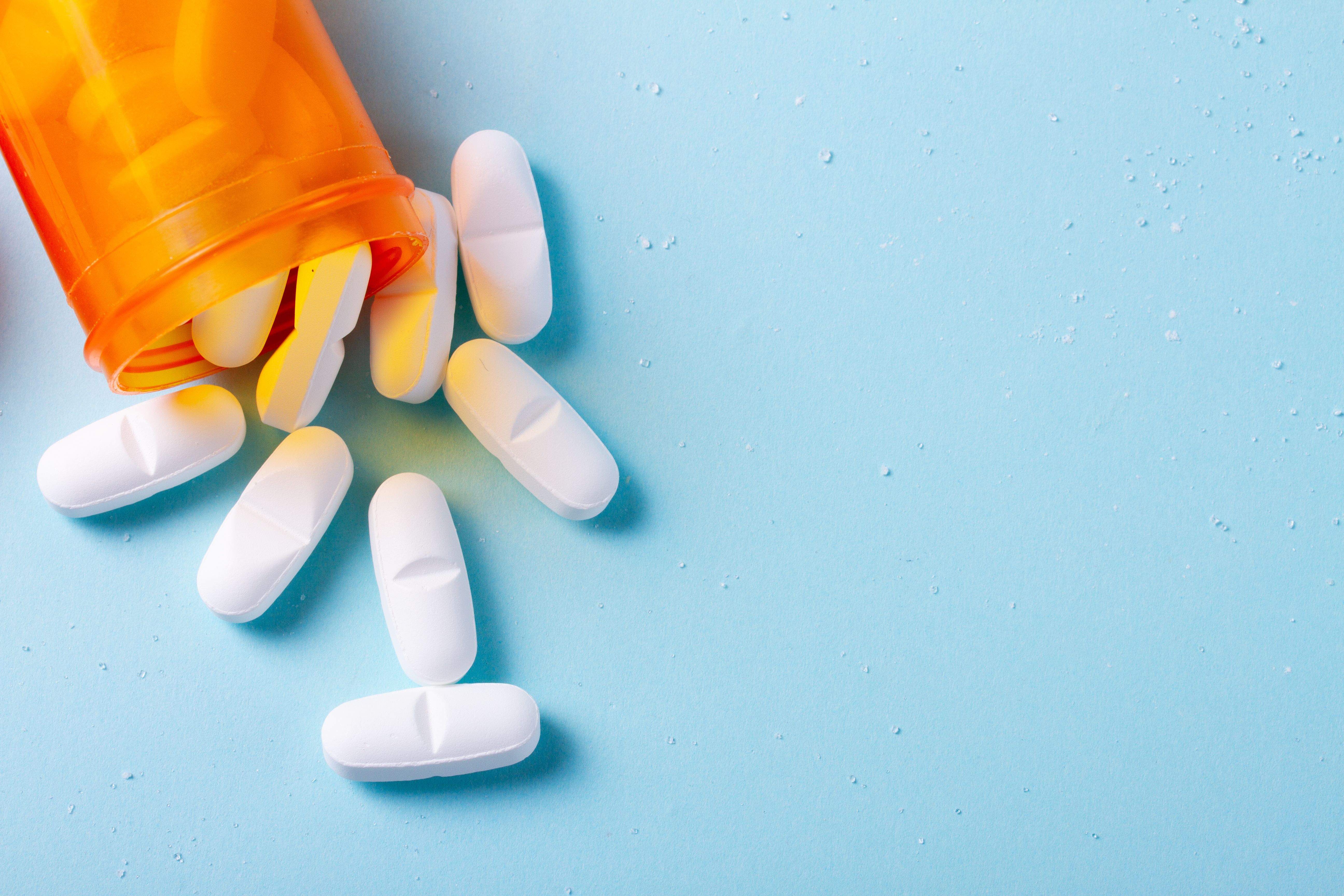 white pills falling out of pill bottle