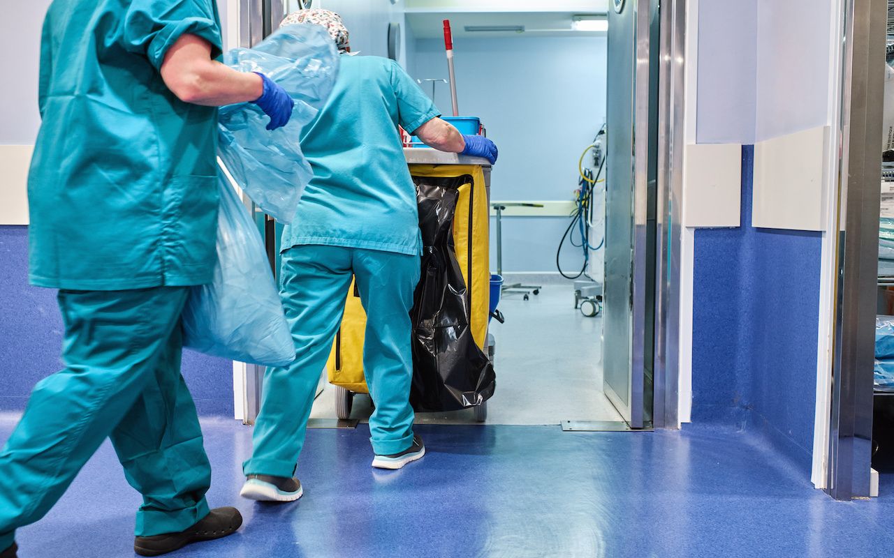 hospital cleaning staff enter an operating room with a cleaning cart: © abraham - stock.adobe.com